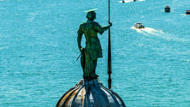 Statue-of-St-George-standing-on-dome-of-cathedral,-Grand-Canal-with-boats
