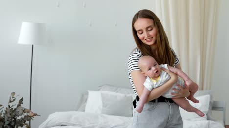 The-concept-of-a-modern-young-family-in-a-white-apartment.-Mom-puts-the-baby-to-bed-singing-him-a-lullaby