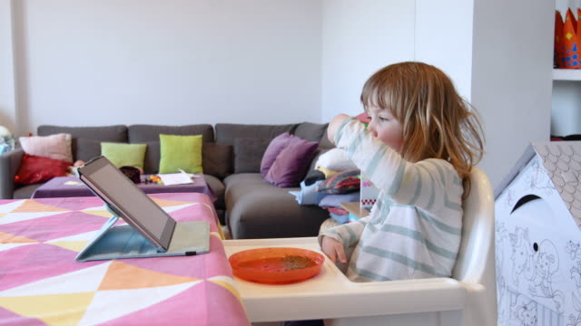 kleines-Kind-Essen-und-Tablet-zu-beobachten