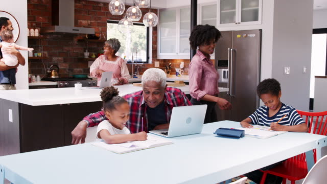 Grandparents-and-parents-helping-children-with-homework-in-busy-multi-generation-family-household---shot-in-slow-motion