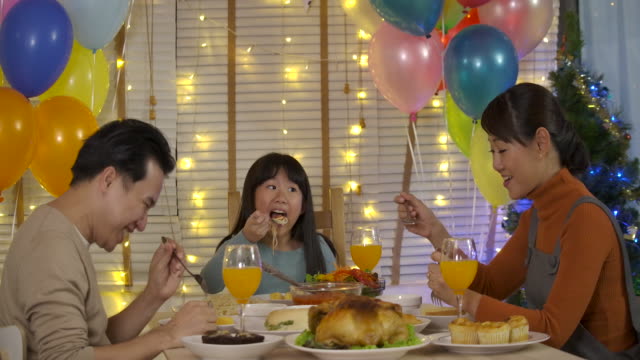 Glückliche-asiatischen-Familie-Weihnachtsessen-zu-Hause-gemeinsam-genießen.
