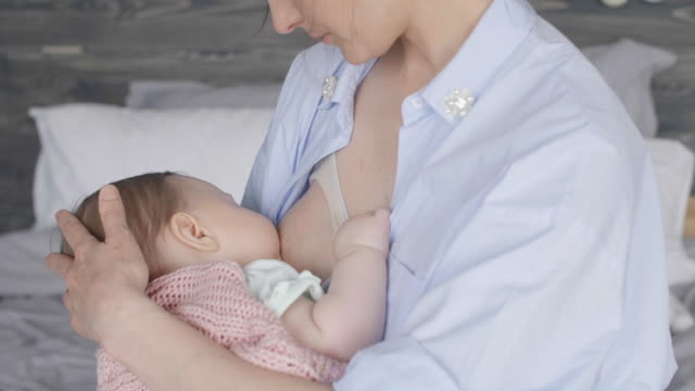 Unrecognizable-mother-breastfeeding-her-baby-on-bed