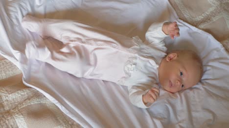 Aktive-wach-Babymädchen-von-zwei-Monaten-auf-Bett