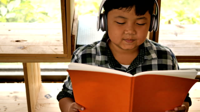 Süße-asiatische-Kinder-ein-Buch-lesen-und-hören-Sie-Musik-zu-Hause.-Bildungskonzept