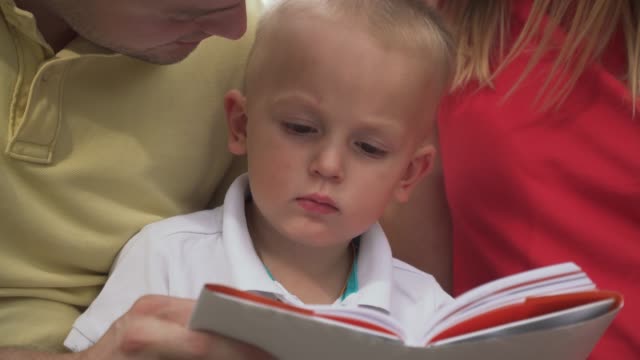 A-little-boy-with-his-parents-rites-a-book.-Close-up