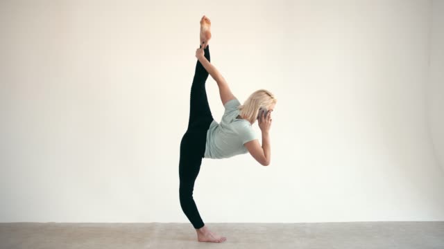 Modell-Größe-plus-Praxis-Yoga-Herr-Pose-und-mit-Smartphone-auf-weißem-Hintergrund