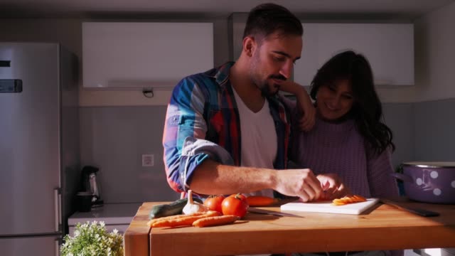Man-arranging-salad-in-the-kitchen-while-girlfriend-is-smiling