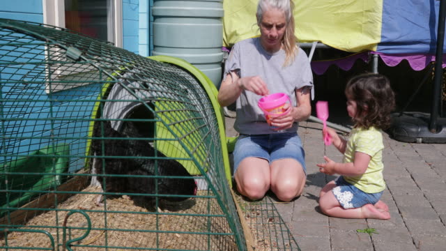 Kleines-Mädchen-helfen-ihr-Oma-Futter-der-Hühner