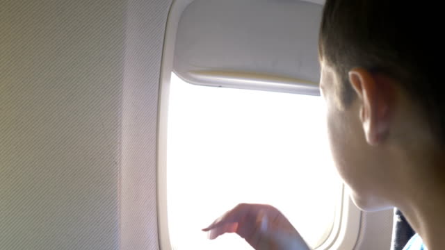 boy-closes-the-porthole-on-the-plane-and-prepares-to-sleep