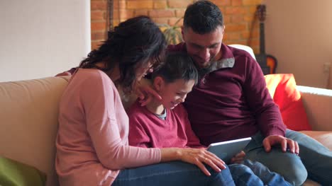 Family-of-three-using-digital-tablet-on-sofa