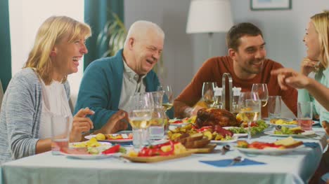 Familiares-y-amigos-en-la-mesa-del-comedor.-Senior-pareja-hablando,-bromeando-y-comer.-Viejas-y-jóvenes-personas-riendo-divertido.