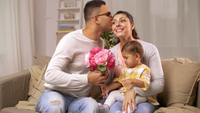 glückliche-Familie-mit-Babymädchen-und-Blumen-zu-Hause