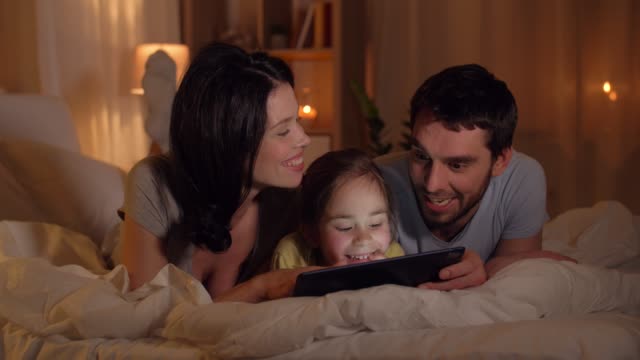 glückliche-Familie-mit-Tablet-pc-im-Bett-zu-Hause