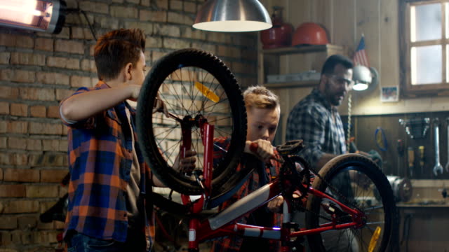 Padre-y-sus-dos-hijos,-reparar-una-bicicleta