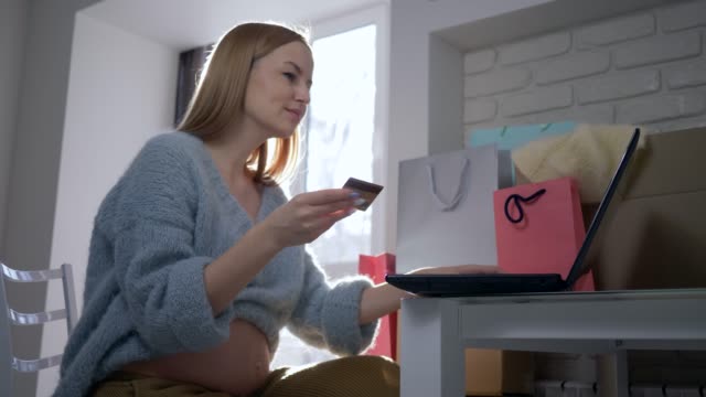 Online-Käufe-verwendet-junge-Mutterschaft-weiblich-mit-Plastikkarte-Laptop-Computer-für-Internet-payment