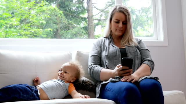 Mother-using-mobile-phone-in-living-room-4k