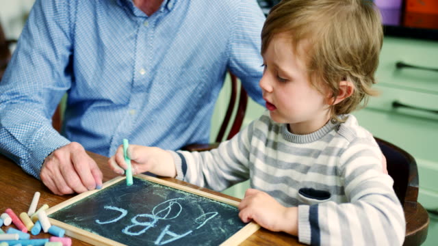 Padre-hijo-de-enseñar-a-escribir-en-la-pizarra-y-la-tiza-usando