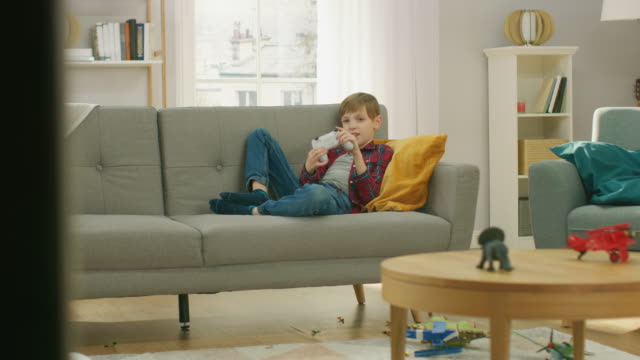 Entzückende-kleine-Junge-auf-einer-Couch-in-Videospiel-auf-TV-Konsole-mit-Joystick-Controller-zu-spielen.-Junge-zu-Hause-im-Videospiel-zu-spielen.