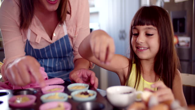 Mädchen-Dekoration-cupcakes-Sie-hilft,-ihre-Mutter-machen