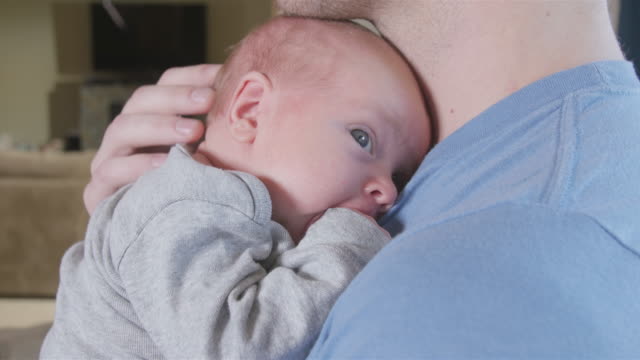 Father-holding-newborn-son-in-living-room