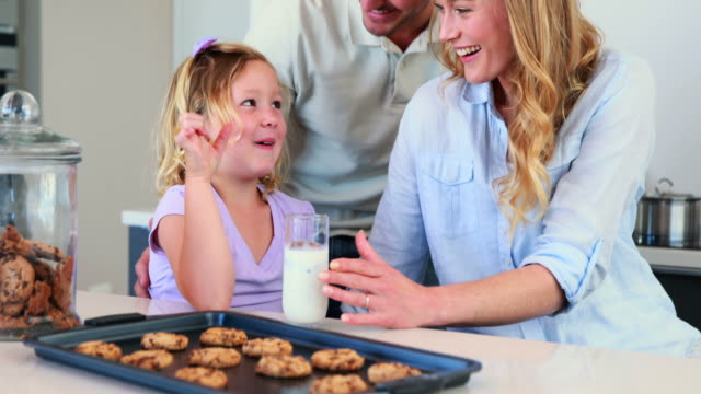 Kleines-Mädchen-mit-Milch-und-Kekse-mit-ihren-Eltern
