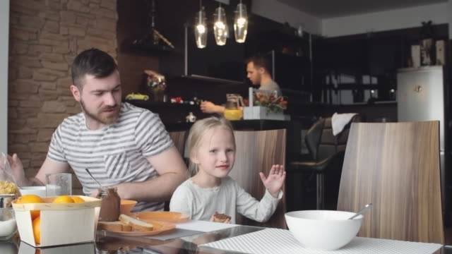 Gay-Eltern-sprechen-mit-kleinen-Tochter-auf-Frühstück