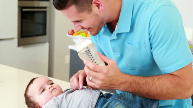 Smiling-father-giving-baby-boy-his-bottle