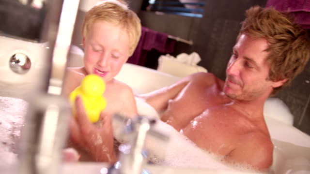 Moderno-Papá-juega-con-hijo-en-baño-de-burbujas-en-su-casa