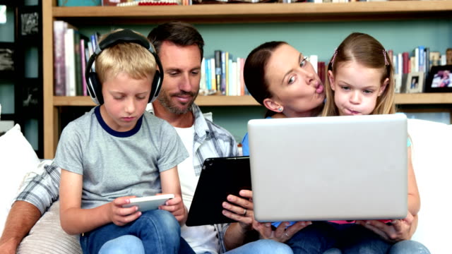 Cute-family-using-technologies-sitting-on-the-couch