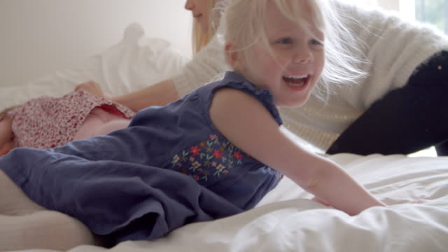 Daughters-Having-Fun-Jumping-On-Parents-Bed-In-Slow-Motion