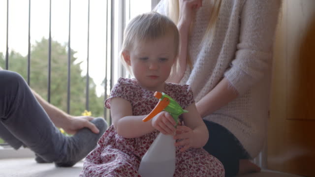 Young-Girl-With-Parents-Playing-With-Plant-Spray