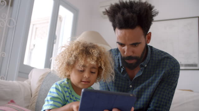 Vater-und-Sohn-sitzen-auf-Sofa-mit-digitales-Tablet