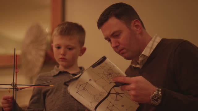 A-father-and-son-reading-instructions-and-building-a-plastic-toy-structure-together-at-home