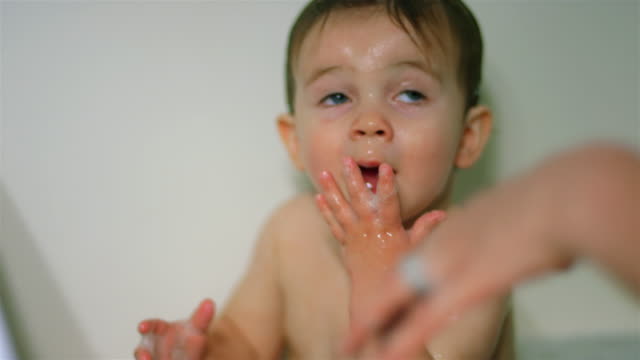 Adorable-little-boy-sits-in-the-bathtub-and-licks-his-soapy-hands