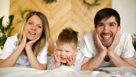 Portrait-of-a-lovely-family-posing-and-smiling-on-bed-in-their-bedroom