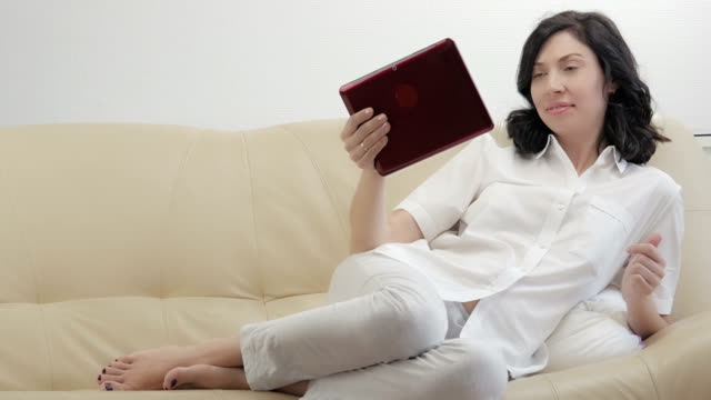 Mujer-joven-usando-tableta-electrónica,-sala-de-estar-con-sofá