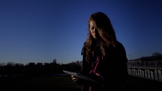 Woman-using-tablet-outside-at-sunset
