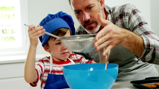 Padre-ayuda-a-muchacho-a-filtrar-utilizando-un-colador-de-harina