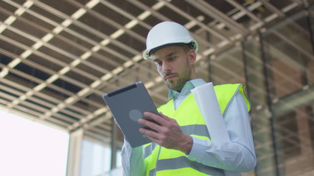 Männlicher-Ingenieur-mit-Tablet-Computer.-Glasbau-oder-Wolkenkratzer-unter-Bau-auf-dem-Hintergrund.