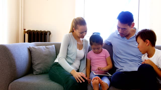 Glückliche-Familie-mit-digital-Tablette-im-Wohnzimmer