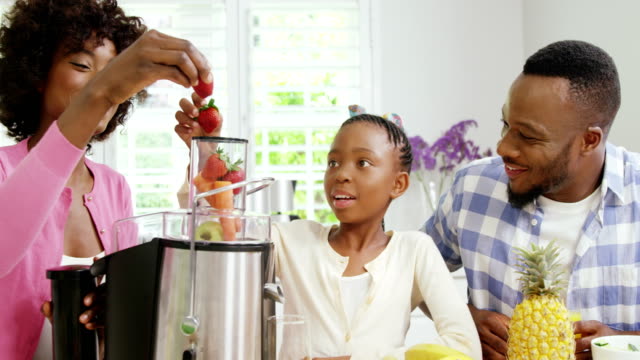 Mother-and-daughter-putting-strawberries-in-juicer