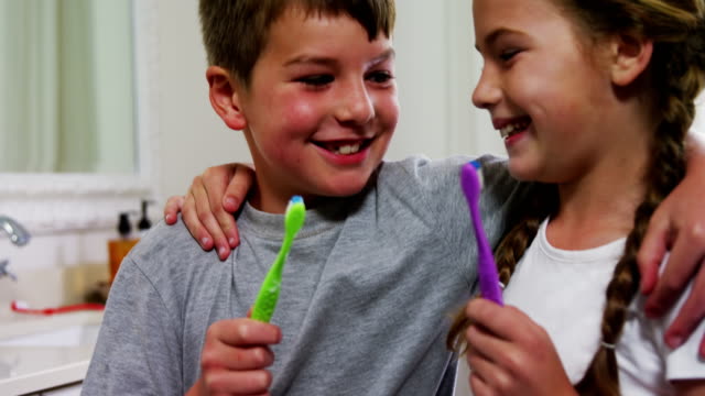 Siblings-holding-their-toothbrush-in-bathroom-4k