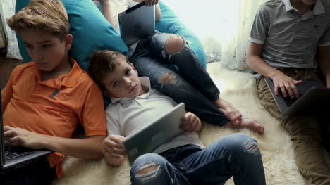 Familia-de-hermanos-pasan-su-tiempo-de-ocio-en-casa-con-ordenadores-portátiles-y-tabletas