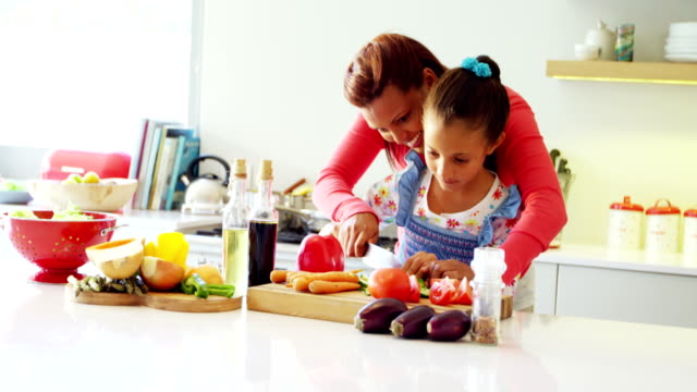 Mother-assisting-daughter-to-chop-vegetables-in-kitchen-4k