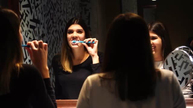 Adolescente-bailando-y-cantando-mientras-se-cepilla-los-dientes-en-el-espejo