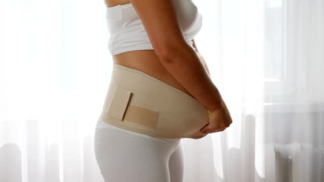 Frau-trägt-einstellbare-Unterstützung-für-pränatale-oder-postpartale-Komfort,-close-up-schwangere-Frau-anziehen-bandage