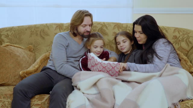 Familia-feliz-lee-cuentos-de-hadas-juntos-en-el-sofá