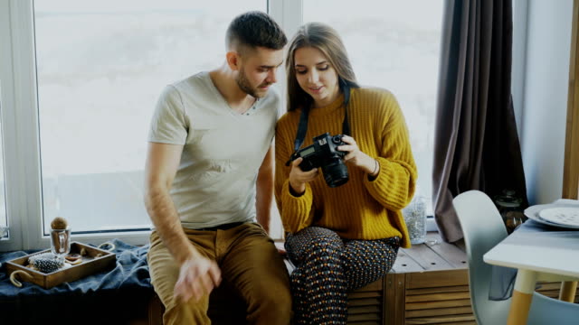 Happy-smiling-couple-watching-photos-from-travel-on-digital-camera-at-home-after-vacation