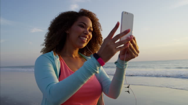 Ethnische-weiblich-mit-Smartphone-am-sunset-beach