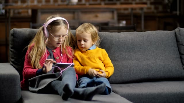 Sweet-little-siblings-using-tablet-pc-on-sofa